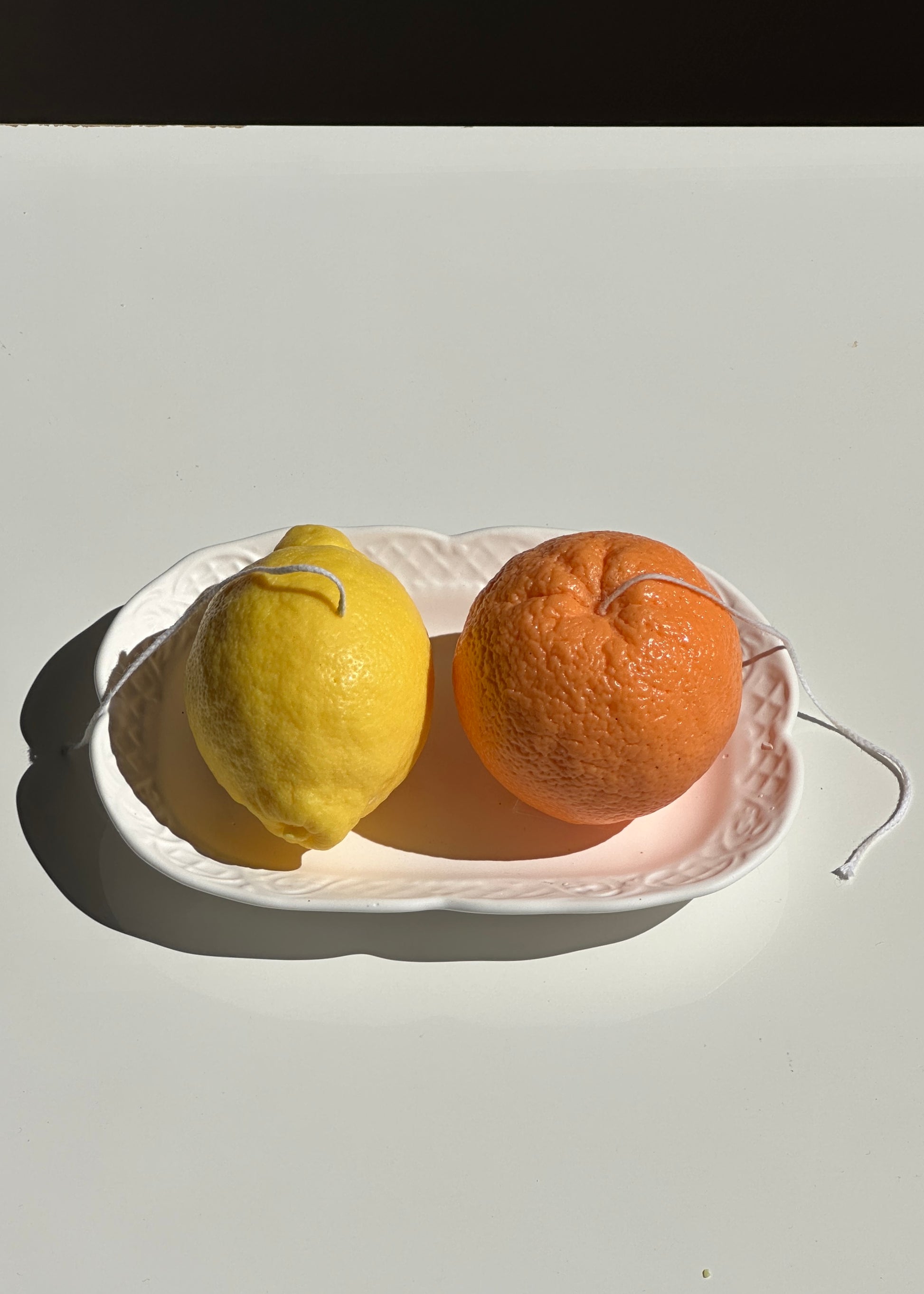 realistic lemon and orange scented candles on an ornate white cement plate